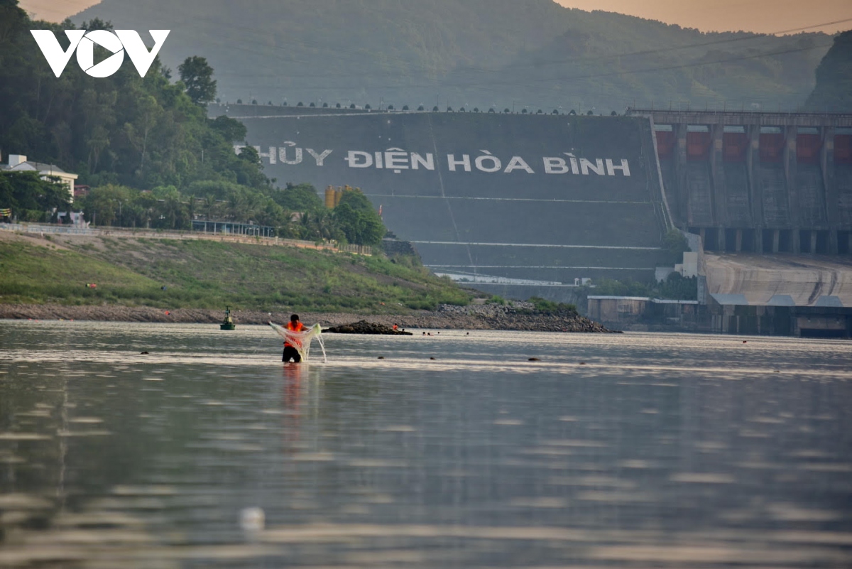 Hồ thủy điện Hòa Bình tiệm cận mực nước chết, người dân đi bắt cá dưới chân đập