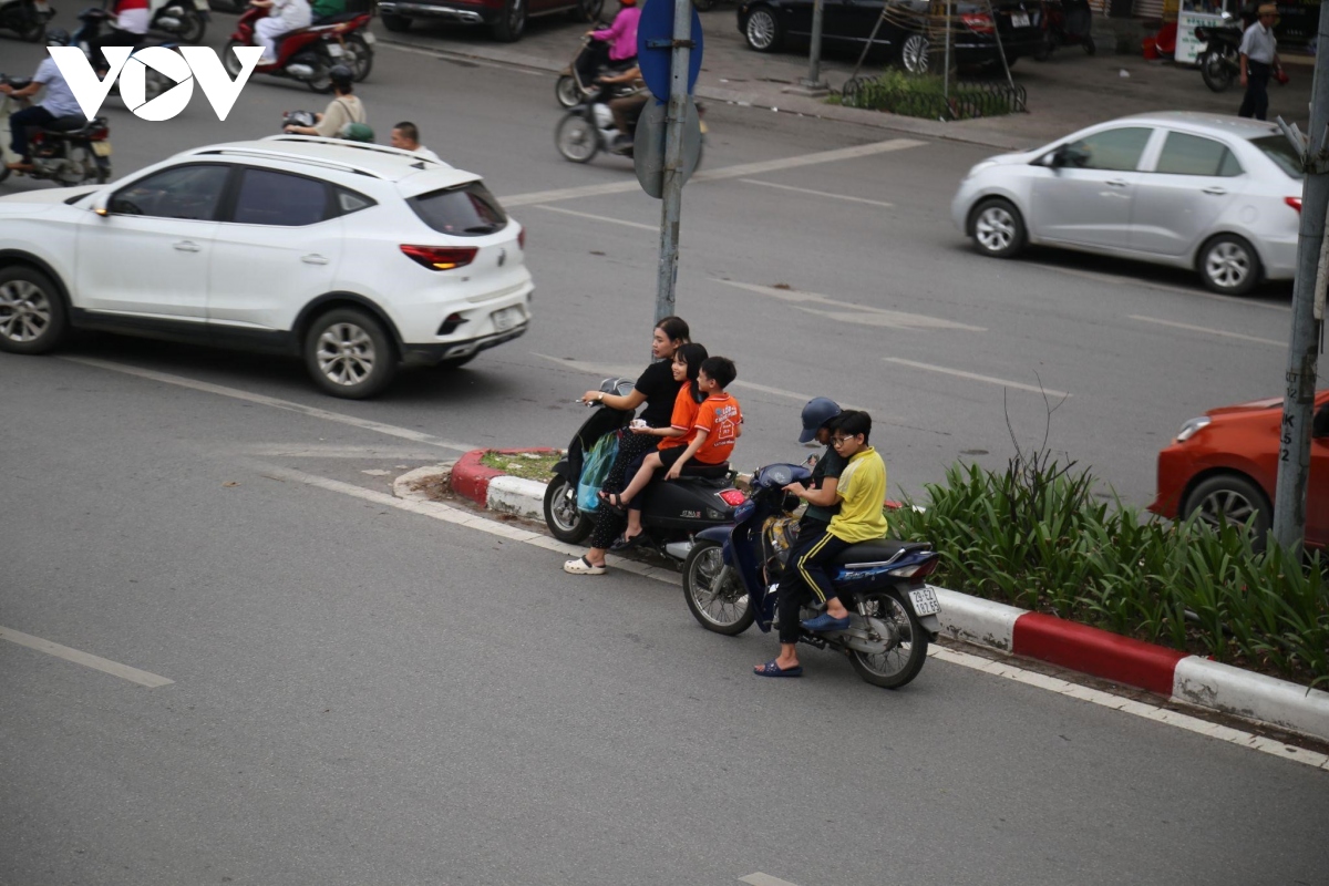 Phụ huynh không đội mũ bảo hiểm, chạy xe ngược chiều đón con tan học ở Hà Nội